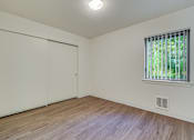 Thumbnail 24 of 27 - A room with a sliding door, a window, and a wooden floor.