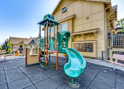 Thumbnail 12 of 33 - A playground with a green slide and a wooden structure.
