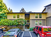 Thumbnail 13 of 27 - A red SUV is parked in front of a two-story house with a garage.