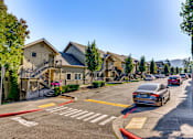 Thumbnail 10 of 33 - A street view of a residential area with houses on the left and cars driving on the road.
