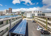 Thumbnail 6 of 12 - A parking lot with solar panels on the roof.
