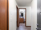 Thumbnail 18 of 29 - A hallway with a wooden door on the left and a grey door on the right.