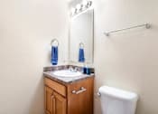Thumbnail 6 of 29 - A bathroom with a toilet, sink, and mirror.