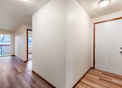 Thumbnail 13 of 29 - A white door is on the right side of a hallway with wood floors.