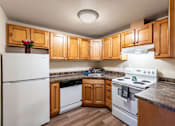 Thumbnail 1 of 29 - A kitchen with a white refrigerator, a white stove, and wooden cabinets.
