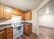 Thumbnail 2 of 29 - A kitchen with a white stove top oven and wooden cabinets.