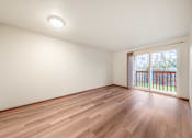 Thumbnail 3 of 29 - A room with wooden flooring and a window with a view of a fence.