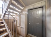 Thumbnail 22 of 29 - A grey door is in a hallway with a staircase.