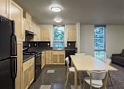 Thumbnail 7 of 22 - A kitchen with a black refrigerator and wooden cabinets.