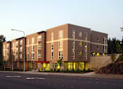 Thumbnail 10 of 22 - A large building with a lot of windows is lit up with yellow lights.