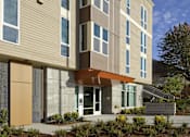Thumbnail 4 of 22 - A modern building with a combination of beige and brown panels.