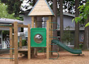 Thumbnail 2 of 3 - A playground with a green slide and a wooden structure.