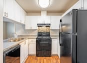 Thumbnail 25 of 40 - a kitchen with white cabinets and black appliances