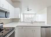 Thumbnail 29 of 40 - A modern kitchen with white cabinets and a stainless steel stove.