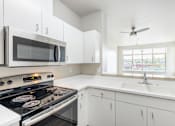 Thumbnail 32 of 40 - A modern kitchen with a black stove top oven and white cabinets.