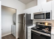 Thumbnail 31 of 40 - A kitchen with a stove, microwave, and refrigerator.