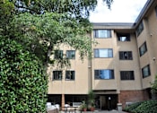 Thumbnail 4 of 18 - A building with a beige facade and a tree in front of it.