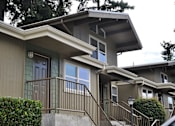 Thumbnail 1 of 3 - A house with a green door and a brown railing.