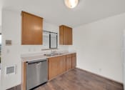 Thumbnail 7 of 20 - an empty kitchen with wooden cabinets and a stainless steel dishwasher