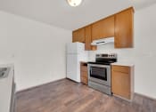 Thumbnail 6 of 20 - a kitchen with wood flooring and white appliances and wooden cabinets