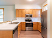 Thumbnail 7 of 40 - A kitchen with wooden cabinets and stainless steel appliances.