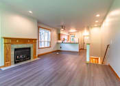 Thumbnail 9 of 40 - A large empty room with a fireplace and wood flooring.