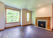 Thumbnail 8 of 40 - A large empty room with a fireplace and two windows.