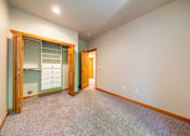 Thumbnail 10 of 40 - A room with a carpeted floor and a wooden door.
