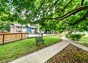 Thumbnail 18 of 19 - A park with a bench and a pathway.