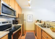 Thumbnail 3 of 22 - A kitchen with a black stove top oven and a black microwave above it.