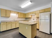 Thumbnail 19 of 24 - A kitchen with a white refrigerator and yellow cabinets.