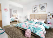 Thumbnail 2 of 6 - A bedroom with a bed, a nightstand, and a wall-mounted shelf with pictures and a lamp.