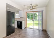 Thumbnail 14 of 19 - A black refrigerator is in a kitchen with wood floors and a ceiling fan.