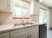 Thumbnail 17 of 19 - A kitchen with a white sink and a window with blinds.