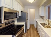 Thumbnail 9 of 18 - A kitchen with white cabinets and a black stove top oven.