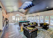 Thumbnail 15 of 18 - A living room with a black couch and a blue rug.