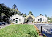 Thumbnail 4 of 18 - A white building with a green roof is surrounded by a grassy area and trees.