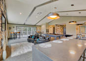 Thumbnail 11 of 18 - A modern kitchen with a large island and a dining area with a table and chairs.