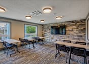 Thumbnail 12 of 18 - A room with tables and chairs and a stone wall.