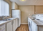 Thumbnail 1 of 9 - A kitchen with white appliances and wooden floors.