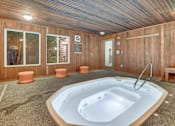 Thumbnail 3 of 9 - A hot tub is in the middle of a room with wood paneling.