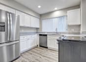 Thumbnail 22 of 31 - A modern kitchen with a stainless steel refrigerator and white cabinets.