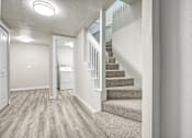 Thumbnail 24 of 31 - A hallway with a staircase and a white door.