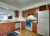 Thumbnail 2 of 6 - A kitchen with wooden cabinets and a white refrigerator.