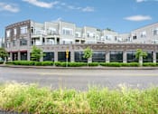 Thumbnail 2 of 40 - A row of modern buildings with a yellow pedestrian crossing sign in front.