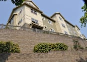 Thumbnail 4 of 33 - A building with a balcony and a wall with plants on it.