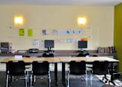 Thumbnail 7 of 33 - A room with a long table and chairs, a computer desk, and a bulletin board with the word "ALL'S" on it.