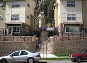 Thumbnail 6 of 33 - Two cars are parked on the street in front of apartment buildings.