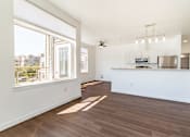 Thumbnail 37 of 40 - A spacious kitchen and living room with wood flooring and white walls.