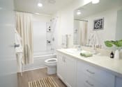 Thumbnail 5 of 6 - A white bathroom with a toilet, sink, and shower.